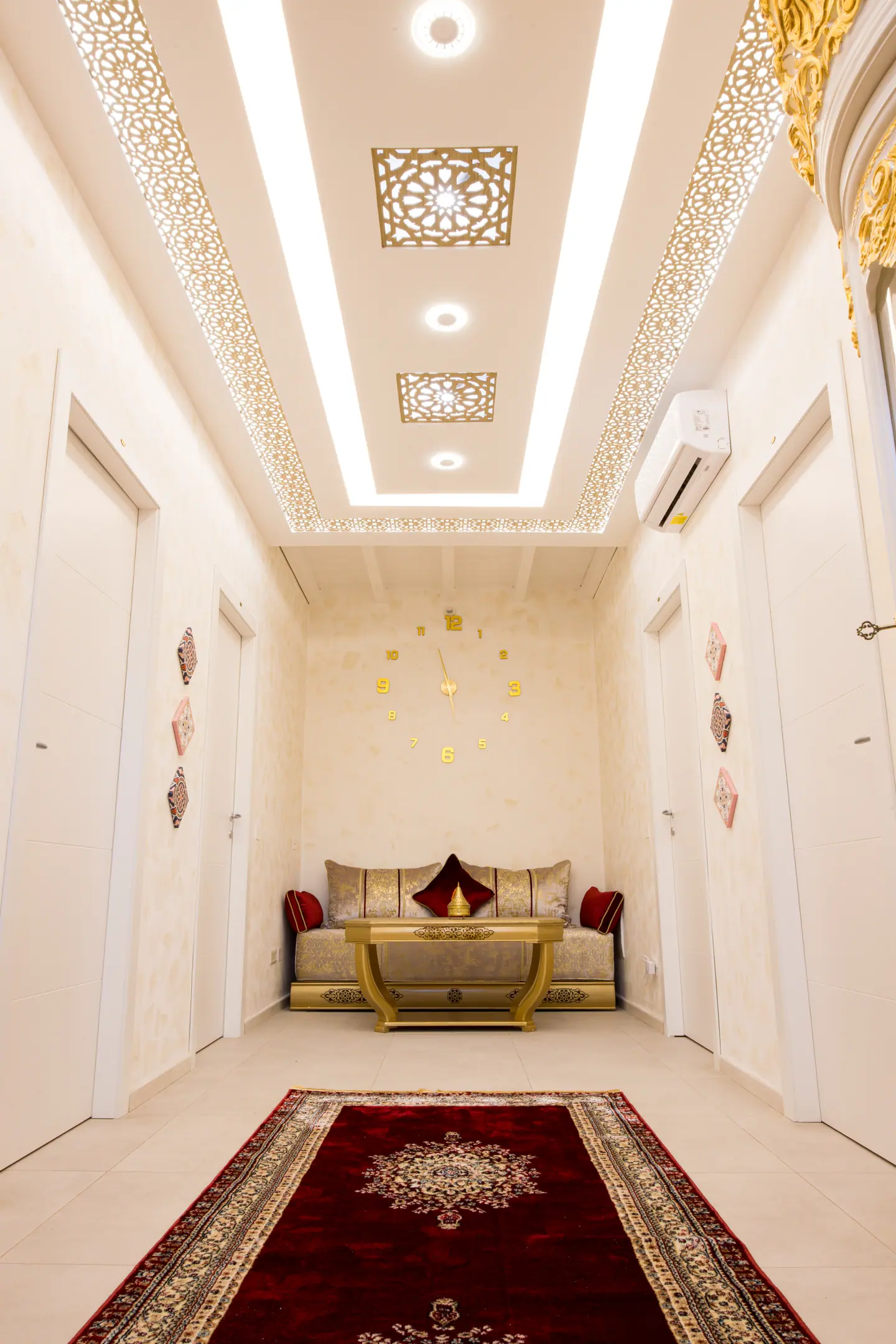 Il corridoio interno: soffitto retroilluminato con traforo dorato, tappeto persiano rosso, divanetto marocchino in fondo e le porte delle camere sui due lati