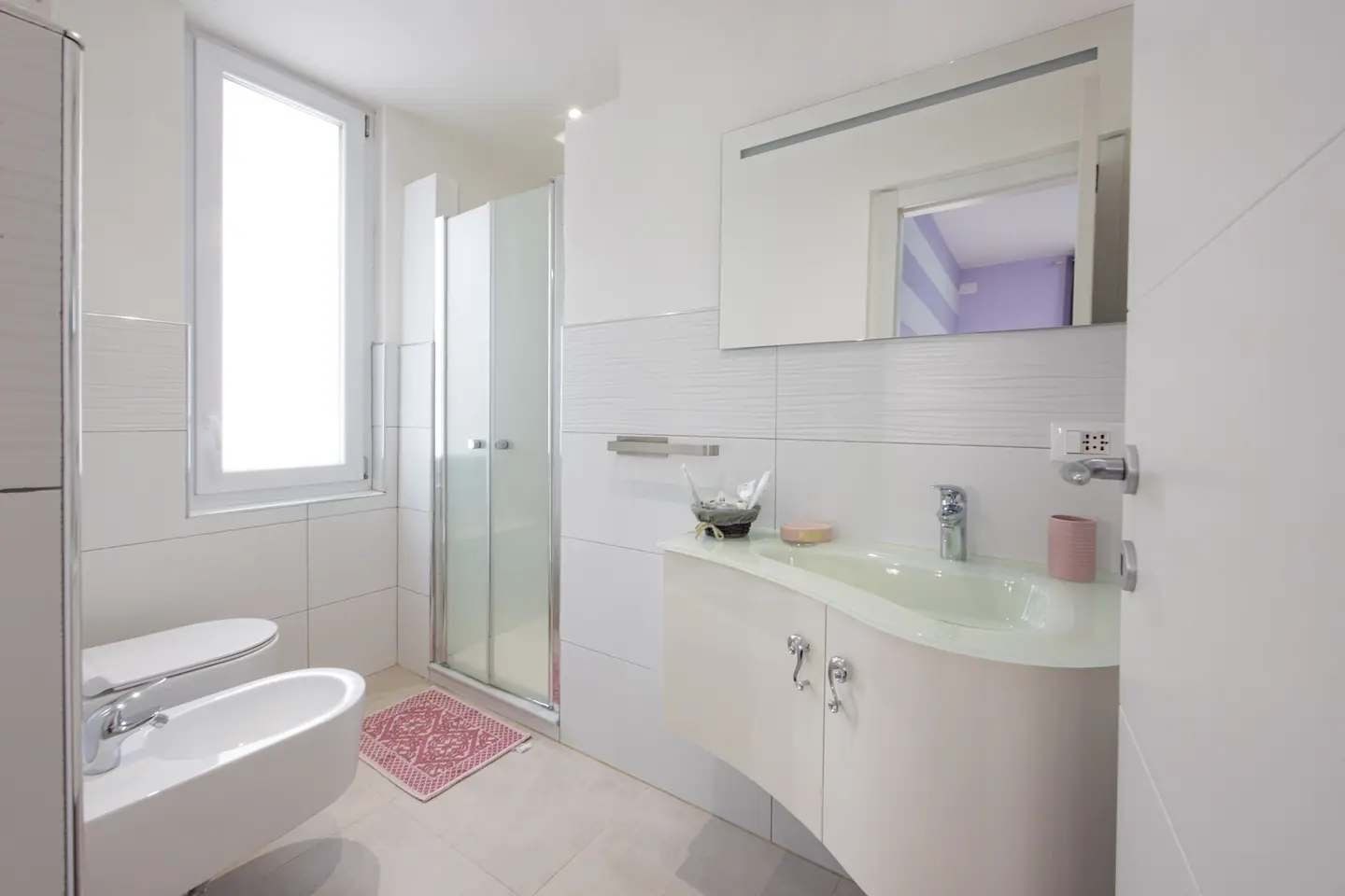 Il bagno privato della camera Tellaro, con lavabo in vetro verde menta e specchio retroilluminato